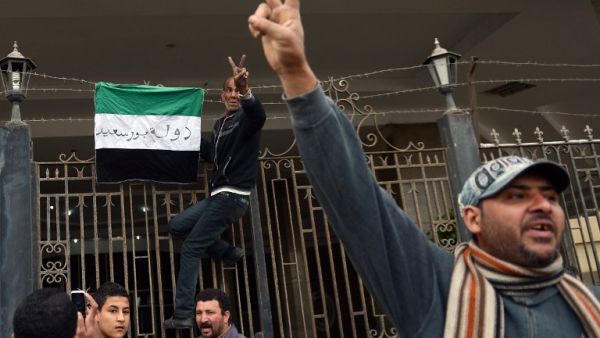 An Egyptian protestor flashes the sign for victory as he puts a flag with writing on it reading in Arabic: "state of Port Said" on the gate of the security headquarters, following the withdrawal of police forces from the main office. (AFP PHOTO / KHALED DESOUKI)
