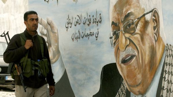 A Fatah movement member stands next to a mural of the Palestinian leader Mahmoud Abbas in the Ain al-Helweh Palestinian refugee camp on the outskirts of the southern Lebanese city of Sidon. (AFP PHOTO/MAHMOUD ZAYYAT)