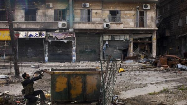 A Syrian rebel aims his weapon as he takes position behind a makeshift barricade during clashes with regime forces in the Salaheddine district of Aleppo. (AFP PHOTO/JM LOPEZ)
