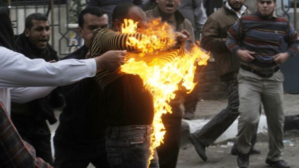 Egyptian members of the Muslim brotherhoods group try to extinguish fire on one of their comrades who he was hit by a molotov cocktail thrown by protesters during clashes in the street that leads to the headquarters of the organization in Cairo on March 22, 2013. Opposition protesters clashed with Islamists near Muslim Brotherhood headquarters in Cairo after activists marched to the building guarded by police and members of Egypt's ruling movement. (AFP PHOTO / STR)