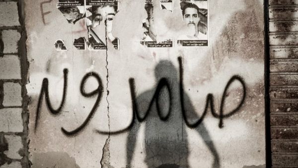 The shadow of a Bahraini protestor is seen over a graffiti which reads in Arabic "steadfast" during clashes with riot police following the funeral of Jaffar Jassim al-Taweel in the village of Sitra, south of Manama on March 27, 2013. 35-year-old Taweel died in the hospital after developing respiratory complications and according to his relatives is due to the inhalation of poisonous tear gas that riot police used during a protest in March 2013. (AFP PHOTO/MOHAMMED AL-SHAIKH)