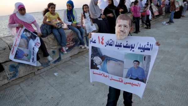 A supporter wears a mask of Egypt's deposed president Mohamed Morsi showing a portrait of a child, victim of the clashes during a protest in the Mediterranean city of Alexandria on August 6, 2013. (AFP)