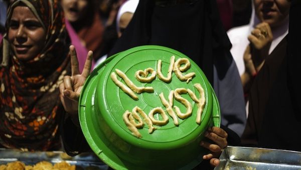 An Egyptian woman displays a pro-Morsi slogan made of pastry to be used for Eid al-Fitr cookies as supporters of ousted president Mohammed Morsi take part in a sit-in outside Cairo's Rabaa al-Adawiya mosque on August 7 (AFP)
