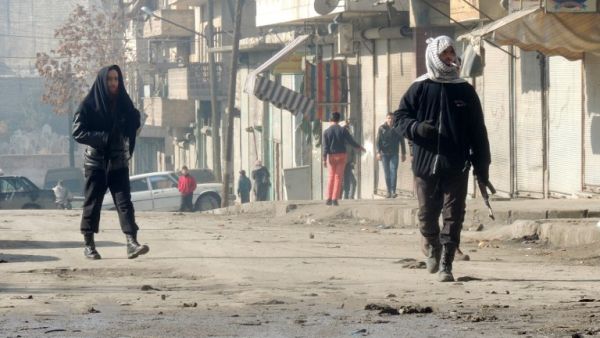Rebel fighters, one holding a weapon, walk in a street on January 7, 2014 in the northern Syrian city of Aleppo. [AFP]