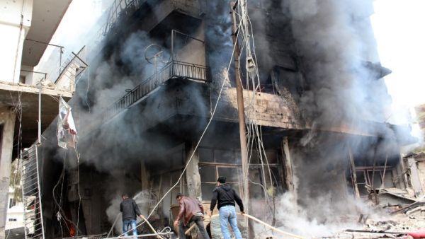 A picture taken on January 12, 2014, shows men trying to put out a fire in a buildings in the city of Daraya, southwest of the capital Damascus. [AFP]