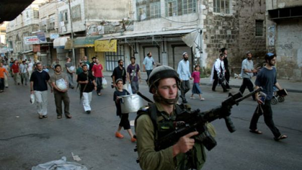 Jewish soldiers guard the 700 Israeli settlers living in the center of Hebron. Under international law, building settlements in Hebron and other West Bank territories is illegal (Courtesy of Mamoun Wazwaz/Maan Images)