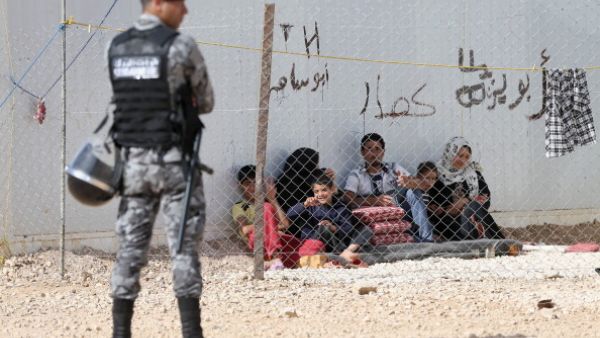 Jordanin Police keep guard as Syrian refugees look on at the King Abdullah Refugee Camp for Syrian refugees 2 kilometers from the Syrian border  (Photo by Chris Jackson/Getty Images) 