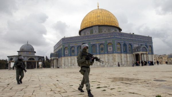 Israeli riot police walk towards stone-throwers as pass the Dome of the Rock mosque following Friday prayers. [Getty Images]