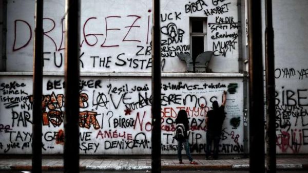 A demonstrator writes slogans on a building painted with graffiti at Taksim square in Istanbul on 6 June 2013. (Photo: AFP - Aris Messinis)