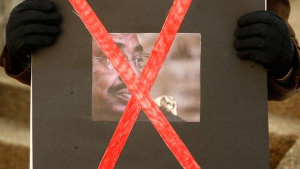 An activist holds a poster of Sudanese President Omar al-Bashir during a protest in front of the Sudanese Embassy in Washington, DC. (Getty)