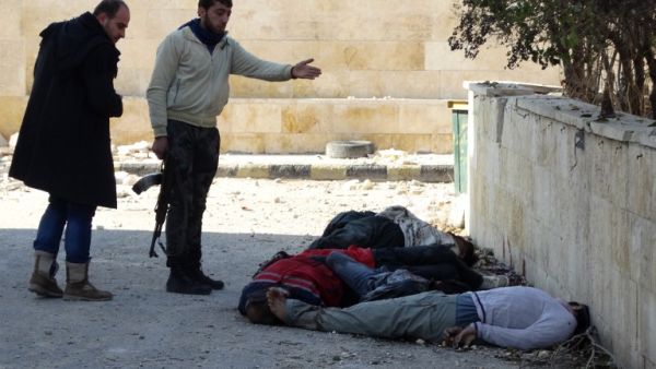 Rebel fighters gesture next to the bodies of handcuffed and blindfolded dead men laying on the ground of the Aleppo headquarters of the Islamic State of Iraq and the Levant earlier this month. (AFP/File)
