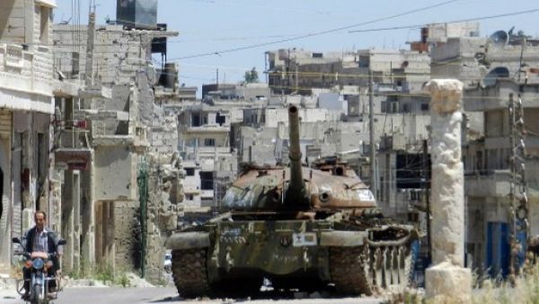 A man rides his motorbike past a burnt out Syrian Army tank in a central Homs province earlier this week. AFP image