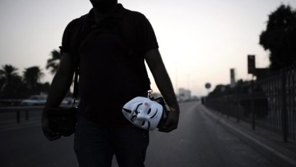 A Bahraini photographer holds a mask of Guy Fawkes used by the anonymous movement during an anti-government protest in the village of Bilad al-Qadeem, in a suburb of the capital Manama. (AFP)

