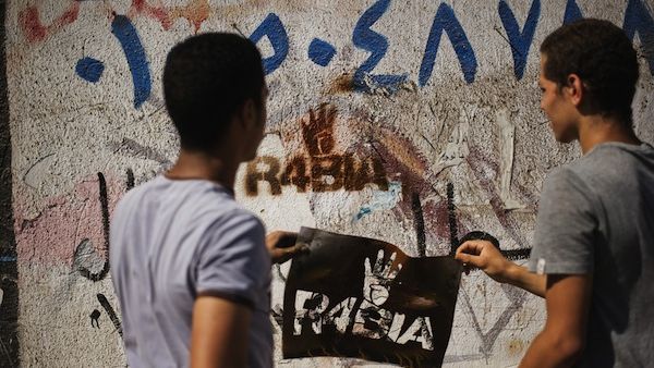 Supporters of the Muslim Brotherhood spray graffiti on the wall reading "Rabia", meaning four in a Arabic, and which has become a symbol to remember those killed in the crackdown on the Rabaa al-Adawiya camp, on August 23, 2013. (AFP)