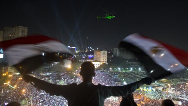 A Egyptian man waves national flags as an army helicopter flies over supporters of Egyptian Armed Forces General Ahmed Fattah al-Sisi rallying at Tahrir Square in Cairo (AFP/KHALED DESOUKI)