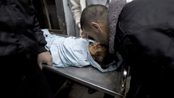 A relative of three-year-old Palestinian girl Hala Abu Sabikha kisses the forehead of the toddler as she lies in the morgue of the hospital in Deir al-Balah in the central Gaza Strip on December 24, 2013. (AFP)