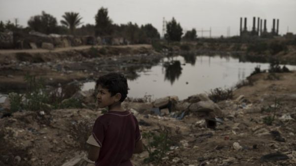A Bedouin boy stands near an open pool of sewage in the garbage filled Wadi Gaza in the central Gaza Strip on November 27, 2013, as the silhouette of the Gaza Strip power plant is seen in the background. (AFP) A Bedouin boy stands near an open pool of sewage in the garbage filled Wadi Gaza in the central Gaza Strip on November 27, 2013, as the silhouette of the Gaza Strip power plant is seen in the background. (AFP)