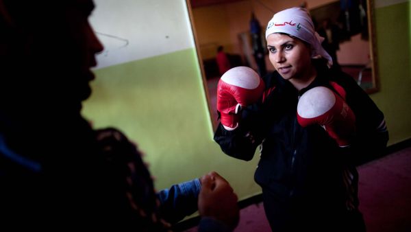 An Afghani woman in a head scarf playing boxing.