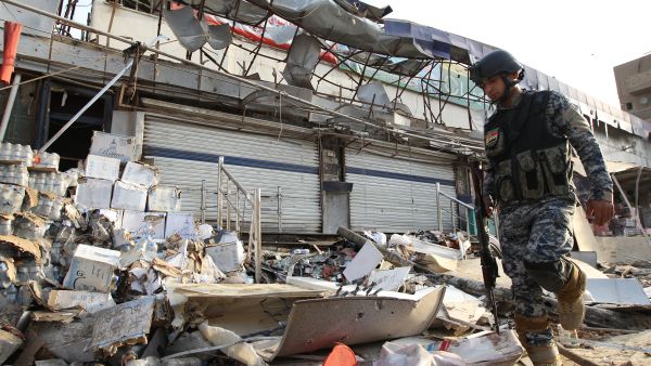 An Iraqi policeman inspects the damage outside a supermarket in central Baghdad's commercial Karrada neighbourhood on June 25, 2013 after a car bomb exploded in the parking area the night before. (Source: AFP/ALI AL-SAADI)