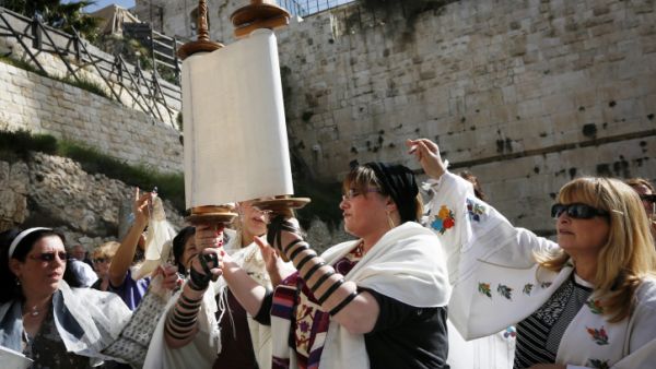 Although allowing women to hold Torah scrolls isn't too common in the Orthodox community, it is not prohibited. [Illustrative photo: Members of Women of the Wall wear prayer shawls as they read from the Torah and pray at Robinson's Arch, near the Western Wall in Jerusalem earlier this year (photo credit: Miriam Alster/Flash90)]