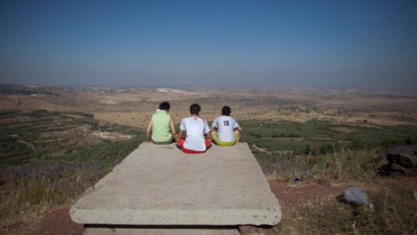 Israelis gaze at the vistas of the nearby Syrian village of Jebata al-Khashabn from an Israeli army post near the village of Buqaata at the Israeli side of the Golan border. 