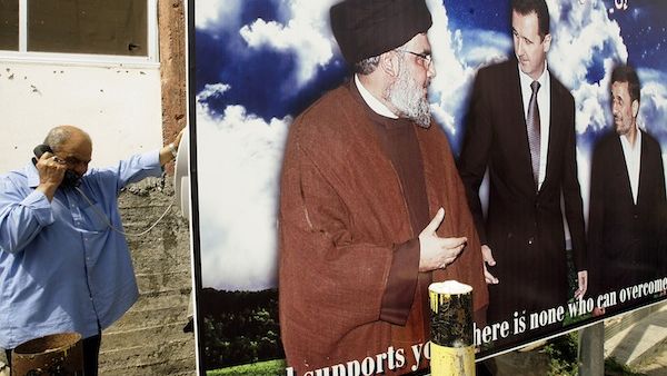  A Lebanese man uses a public phone near a poster featuring Syrian President Bashar Assad, Hezbollah chief Hassan Nasrallah and Iran president Mahmoud Ahmadinejad last week in the southern Lebanese city of Naqura. AFP Photo