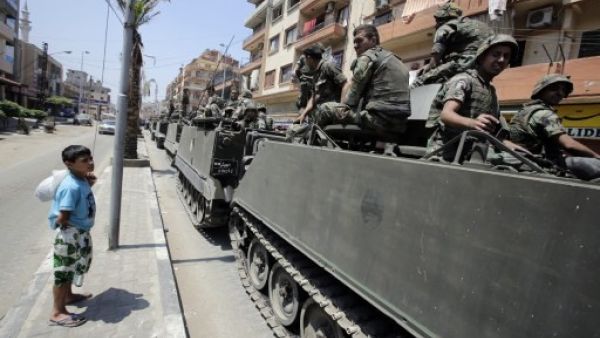A boy watches Lebanese soliders as they drive between the Sunni and Alawite sections of Tripoli. AFP