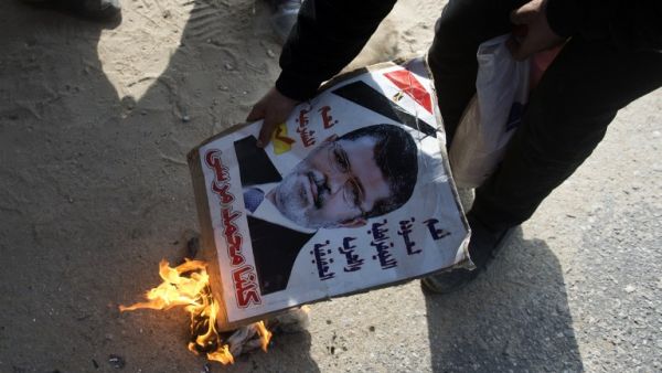 An opponent to the Muslim Brotherhood set fire to a portrait of ousted president Mohamed Morsi during a demonstration outside the Cairo police academy where his trial was set to take place before it was postponed until Feb. 1, 2014. (AFP)
