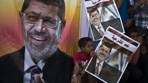 Supporters of deposed Egyptian president Mohamed Morsi (portrait) watch a football match between the two main Cairo protest camps by members of the Muslim Brotherhood and backers of the ousted Islamist leader set up at the Nahda and Rabaa al-Adawiya squares, on August 11, 2013 in Cairo's al-Nahda square/ (AFP)