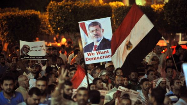 Egyptian supporters of the deposed president Mohamed Morsi hold his portrait and wave the national flags during a demonstration against the government in Cairo on July 31, 2013. (AFP/Getty)