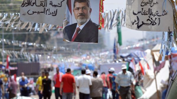 Supporters of Egypt's deposed president Mohamed Morsi walk past his portrait in Cairo (AFP/FAYEZ NURELDINE)