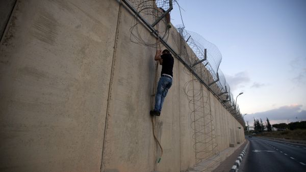 A Palestinian man jumps using a rope over a section of Israel's controversial concrete barrier that separates the West Bank from Jerusalem on August 12, 2013, in Beit Hanina, in Israeli annexed east Jerusalem. (AFP)