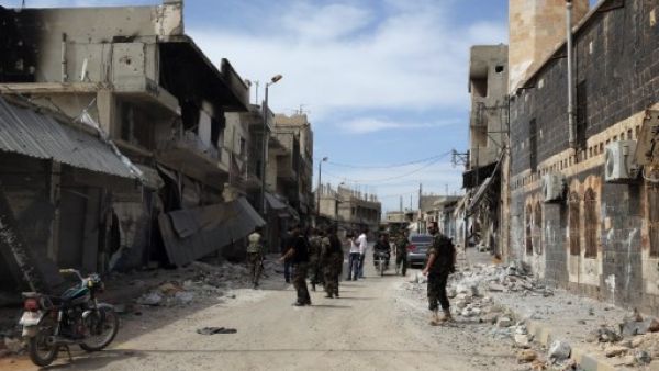 Syrian army soldiers assess a damaged street in the town of Qusair, in Syria's central Homs province on  Friday, as the regime sought to 'remove' all remaining rebel strongholds in the country. AFP 