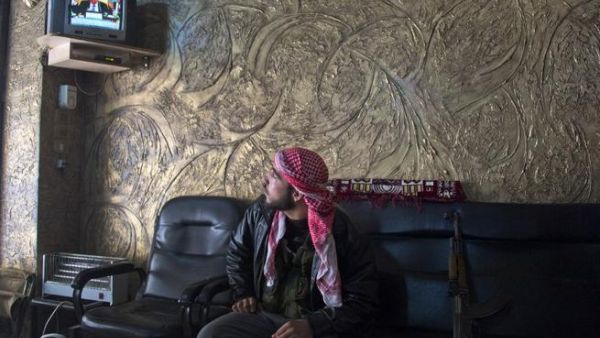 A rebel soldier watches the satellite TV news, waiting to learn his country's fate