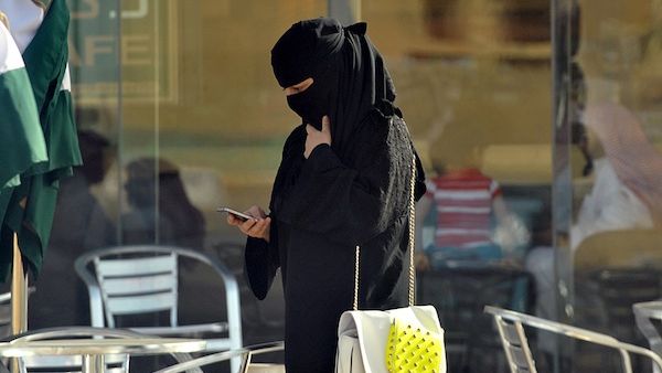 A Saudi woman looks at her mobile as she walks through a coffee shop in the capital Riyadh last week. The Saudi government has enacted a switch in the weekend in Saudi, making the working week go from Sunday-Thursday, in line with the majority of the Arab world. (AFP)