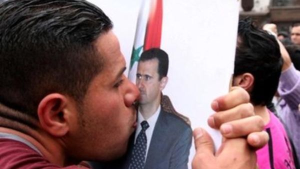 A pro-government supporter kisses a poster of Syrian President Bashar al-Assad.
