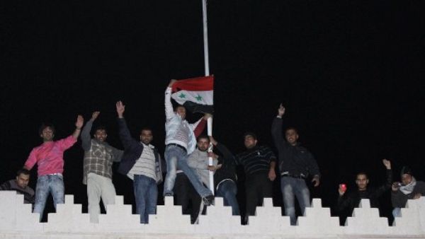 Syrians raise the national flag on the roof of the Qatar Embassy in Damascus on November 12, 2011.