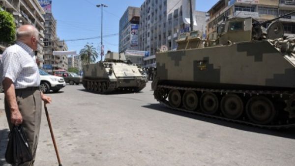 A man looks at tanks of Lebanese Army Forces patrolling on June 6, 2013 in a street of the eastern Lebanese city of Tripoli. AFP Photo