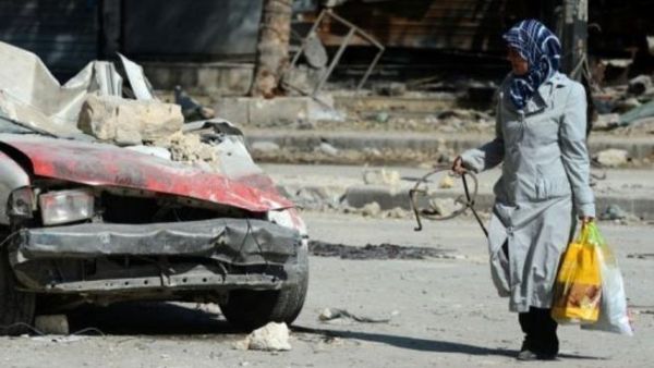 امراة تمر من امام حطام سيارة في حلب