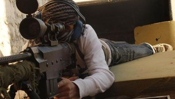 مقاتل من الجيش السوري الحر يصوب سلاحه وهو يتحصن في وضع دفاعي بقرية في ريف حلب
