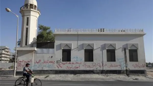 بحريني يمر بدراجة أمام مسجد في قرية دراز غربي المنامة كتبت على جدرانه الخارجية شعارات مناهضة للحكومة البحرينية