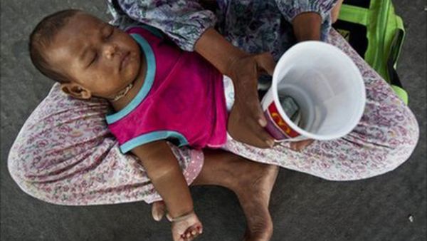 The reality of a tired baby on the lap of a beggar is harsh and depressing. (AP)