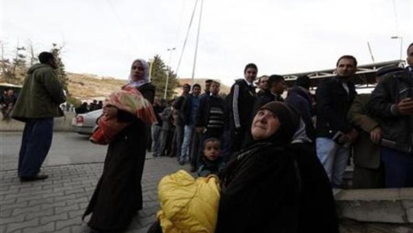 
فلسطينيات ممن كن يقمن في مخيم اليرموك بسوريا ينتظرن بينما يقف الرجال في طابور لختم وثائق دخولهم الى لبنان عند نقطة المصنع الحدودية بين سوريا ولبنان يوم الثلاثاء