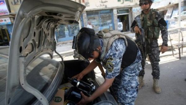الشرطة العراقية تفتش صندوق سيارة على حاجز وسط بغداد 

