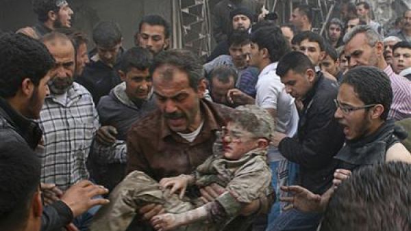 رجل يحمل طفلا انتشل من ركام منطقة تعرضت لقصف في حلب
