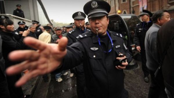 شرطي يطلب من مجموعة من الاشخاص الذين تجمعوا في شارع في شنغهاي الاحد 27 شباط/فبراير التفرق
