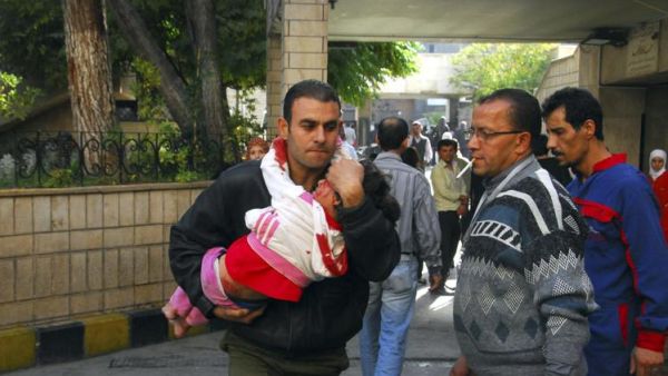 رجل يحمل طفلا اصيب في الانفجار الذي وقع عند مدخل مبنى المؤسسة العامة للخط الحديدي