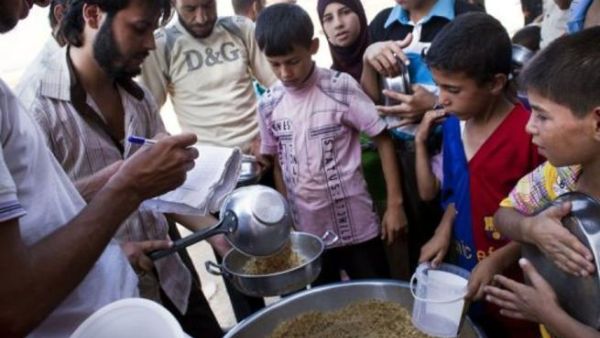 نازحون سوريون يستلمون وجبات غذائية قرب معبر السلامة عند الحدود التركية السورية
