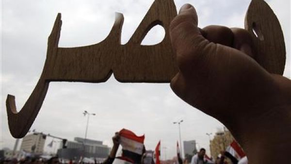 متظاهر مصري يحمل قطعة خشب منحوتة على اسم مصر في ميدان التحرير