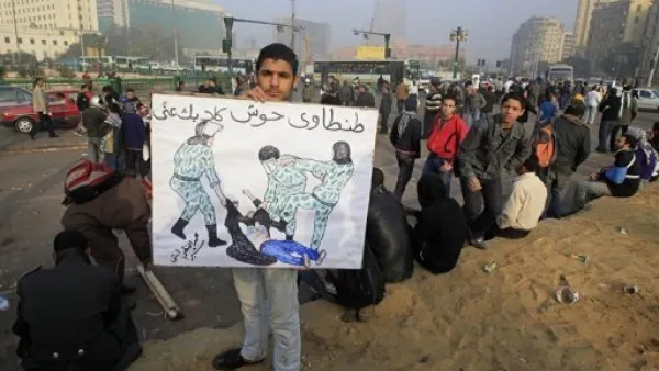 متظاهر مصري يحمل لافتة عليها صورة الناشطة التي تعرضت للضرب وللتعرية من ملابسها من قبل قوات الامن الاسبوع الماضي
